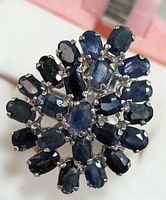 Close-up top view of the sapphire cluster on the silver ring showing the oval blue stones in floral arrangement.