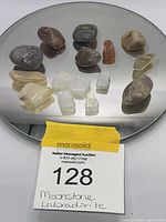 Multiple tumbled stones displayed on a circular mirror including various moonstones and labradorite stones in irregular shapes.