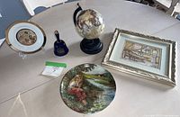 Five assorted collectible items on table: Chokin-style plate, small globe, framed picture, decorative plate, blue glass bell.