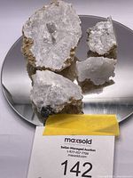 Clear quartz geode mineral sample broken into several pieces shown on reflective surface with MaxSold lot number card.