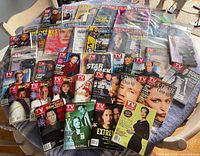 Collection of TV Guide magazines laid out on table, showing covers with Star Trek series, X Files, and other sci-fi TV shows. Some magazines are still sealed in plastic.