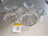 Clear crystal decorative bowls and plate set arranged on a table, showing intricate cut glass designs.