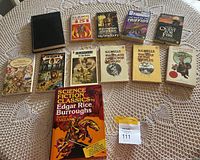 Overview of the entire collection of classic novels arranged on a lace tablecloth showing a diverse set of titles by noted authors.