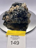 Photo of large raw black tourmaline mineral placed on a reflective surface showing overall size and shape