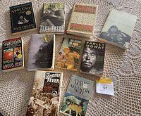 Overview of 11 novels by various authors including Farley Mowat, Stuart McLean, David Guterson, Pierre Burton, and Angus Reid, arranged on a crocheted surface.