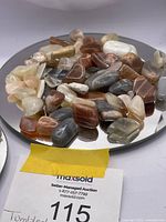 Close-up image showing various tumbled moonstone pieces in different natural shades placed on a reflective surface.