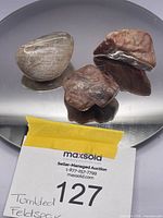 Set of 3 tumbled sunstone feldspar stones displayed on a reflective surface with a Maxsold auction card in view.