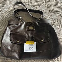 Front view of large dark brown leather purse with two front flap pockets and Tommy Hilfiger label.