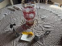 Photo showing the Bohemian glass vase alongside the tin rose and pewter candle snuffer on a crocheted lace tablecloth.