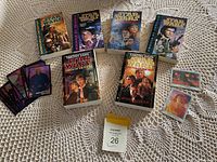 Photo showing 7 vintage Star Wars paperback novels and two sets of Star Wars collectible cards on a lace tablecloth.