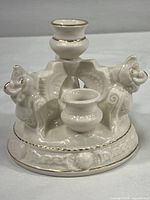 Side view of white porcelain candle holder featuring two dragons and candle spots with gold trim.