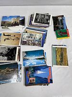 Multiple stacks of assorted vintage postcards showing varied locations and themes