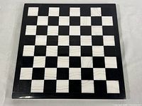 Full view of the square black and white marble chess board, showing the overall pattern and size.