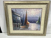 Framed impressionist painting showing several colorful sailboats docked by stone harbor under pink sky.