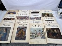 Overview photo of 16 paperback art books featuring famous masters, laid out on the floor. Each titled with an artist's name and showing a color print cover.