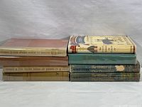Side view of stacked hardcover books by John Steinbeck showing titles and condition.