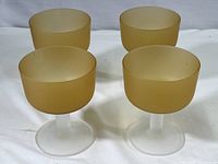 Set of 4 frosted amber and white stemmed glasses, all intact and shown from an overhead angle on a white cloth background.