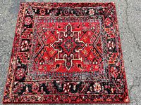 Top view of vintage Hamadan rug red and multi-color design on pavement.