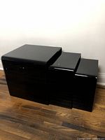 View of the set of three black glass nesting tables, nested together showing size progression from largest to smallest.
