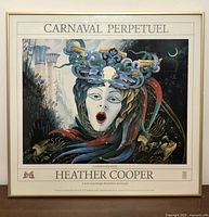 Framed lithograph poster with surreal face and headdress, titled 'Carnaval Perpetuel' by Heather Cooper shown fully.