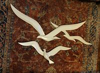 All three white resin seagull wall sculptures laid on patterned rug showing wingspan and relative sizes