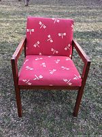 Front view of the chair showing red upholstery with white dragonfly prints and wooden frame