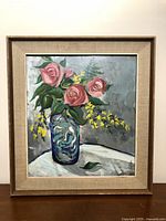 Full frontal photo of the framed oil painting showing flowers in vase with beige fabric inlay frame and wood outer frame