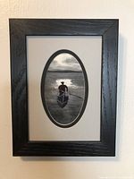 Framed fibre art showing a fisherman in a boat from a distance.