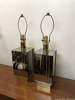 Pair of vintage post modern mirrored rectangular block lamps with metal sockets and bases, placed on wooden surface.
