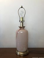 Vintage light pink glass table lamp on brass base, unlit, showing shape and color