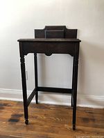 Front view of dark wooden side table with four legs and back panel