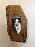 Full view of the small dog portrait embedded in the live edge wood frame hanging on a white wall.