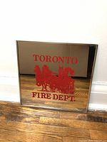 Front view of square mirror with red horse-drawn fire engine graphic and 'TORONTO FIRE DEPT.' text