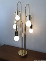 Lamp lit, frontal view showing six illuminated globe bulbs and overall design