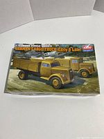 Front view of the boxed model kit showing box art with two yellow German cargo trucks from early and late WWII.
