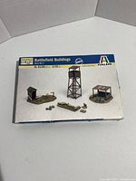 Box top showing the Italeri 1:72 Battlefield Buildings model kit with painted sample models of the watchtower, hut, and sandbag defenses.