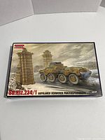 Box front showing painted illustration of WW2 German Sd.Kfz.234/1 armored car in winter conditions with gate pillars in background.