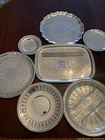 Seven assorted silver-plated trays displayed