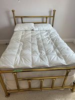 View of bed frame with bedding and pillows on mattress