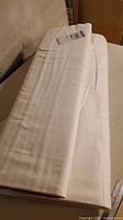 Single folded bolt of white fabric with tag visible