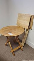 Round folding wood table assembled, showing natural wood slatted top and foldable legs.