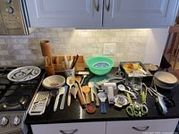 Overview of all kitchen items arranged on countertop showing the mix of utensils, bowls, glasses, and measuring tools.