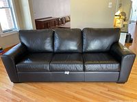 Front view of the entire three-seat black leather couch