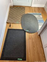 Four floor mats of different styles arranged on wood floor near door