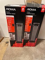 Pair of two new Noma digital ceramic heaters in original boxes, displayed upright on a concrete floor.