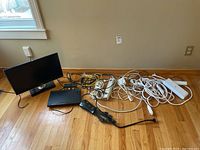 Lot contents showing Samsung 22-inch monitor, Sony DVD player, and multiple cords laid on wooden floor