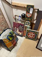 Overview photo showing all four stitched artworks leaning against the wall with a colorful bag on the floor containing supplies.