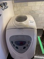 Front angle view of the white Sunbeam bread maker showing the top window and overall condition with some dirt marks.