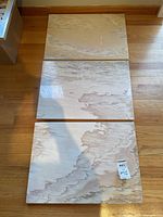 Photo showing all three rectangular travertine slabs laid out on wooden floor showing natural stone patterns and colors.