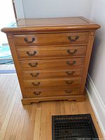 Front view of the six drawer wooden dresser showing metal handles and overall condition.